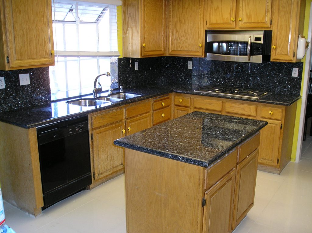 Black granite kitchen countertops and island with a full backsplash